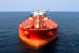 "Close up aerial photo of a large oil tanker, with an oil rig in the far distance."